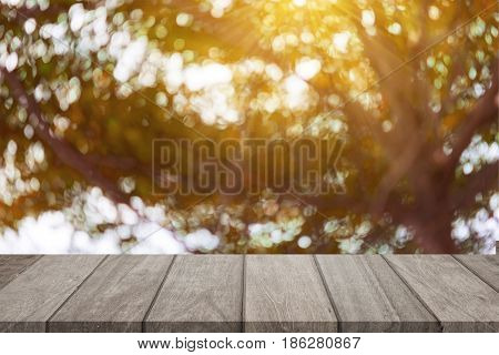 Empty wooden table top and sunny blurred bokeh background for product displa
