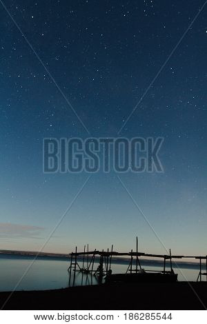 Night view of the pier by the river and the starry sky