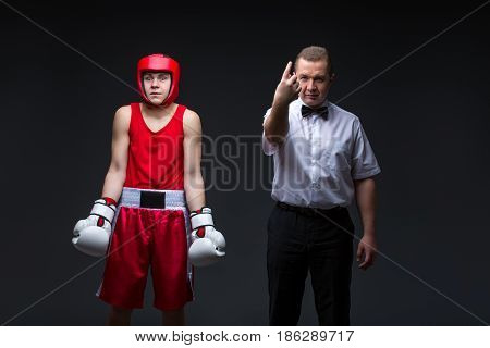 Referee giving penalty point to young boxing sportsman before fight. Studio shot on black background. Copy space.