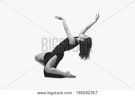 Beautiful modern dancer young woman in black flyings fabrics making dance moves. Isolated on white background. Copy space. Monochrome.