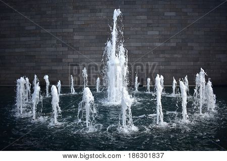 background circular water fountain against grey brick wall