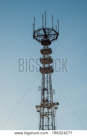 TV tower with antennas, telecommunication building, against a blue sky,