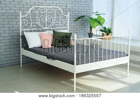 Large White Metal Frame Bed With Decorative Metal Headboard And White, Pink And Green Pillows On It.