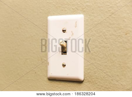 Dirty old lightswitch mounted on a wall inside a house.