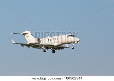 A small white business aviation aircraft landing to airport runway with the chassis released