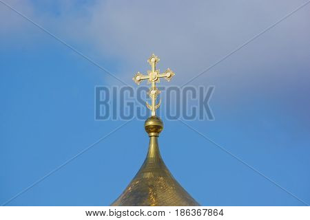 Golden Russian orthodox cross at the orthodox church roof top against blue sky