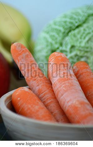 Raw carrot in a bamboo pot with cabbage in background