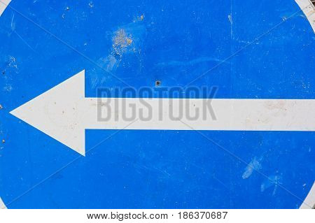 Close up road sign with white arrow to left on blue background