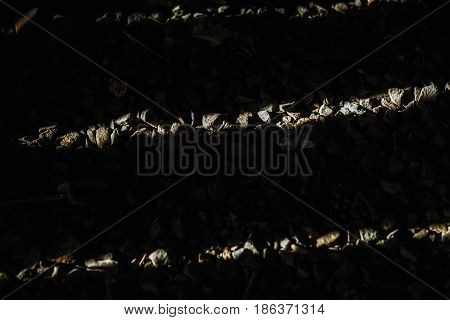 Background made of close up photo of crushed stone with dark shadow of sun shinig through wooden planks