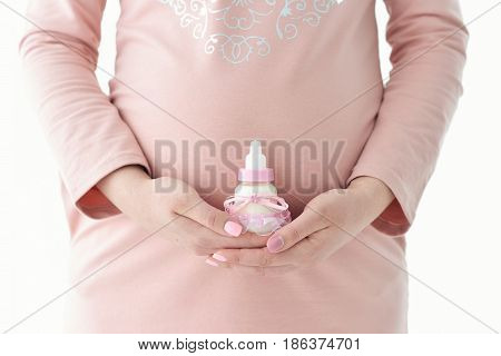 Belly of a pregnant woman Hands hold pink Bottle of milk