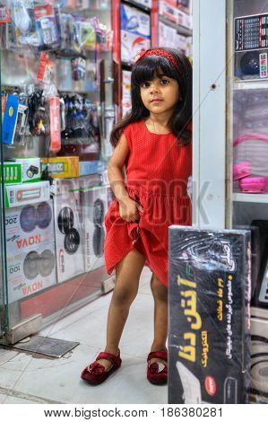 Bandar Abbas Hormozgan Province Iran - 16 april 2017: One unknown little girl about five years old is standing on doorstep of an electronics store portrait in full growth for editorial use only