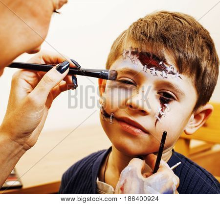 little cute child making facepaint on birthday party, zombie Apocalypse facepainting, halloween preparing concept, lifestyle people close up