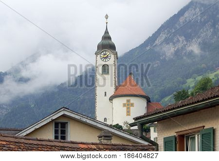 Church of Fluelen in front of foggy mountain ridges at Lake Luzern Switzerland