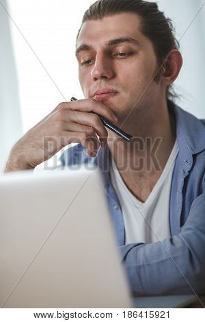 portrait of concetrated man with laptop at his home, window on background