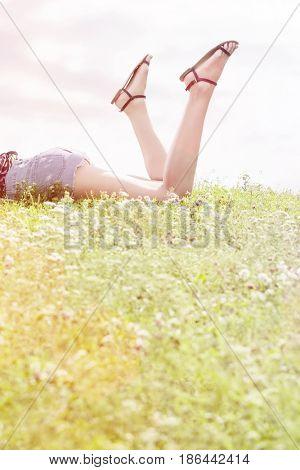 Low section of woman lying on grass against sky