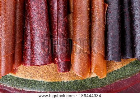 Colorful fruit leather rolls on mats of crushed fruit ( tklapi ). Fruit candy - pastille. Top view.