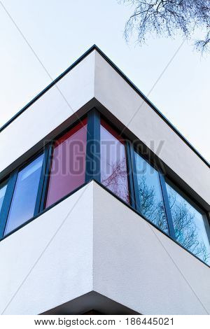 Red and white rendered modern building facade on a bright sunny day with clear sky. Abstract background.