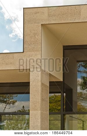 Building facade with elegant Birttish Portland Stone columns. The windows of the building reflecting the sky and trees