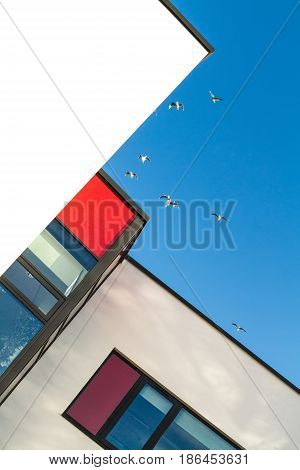 Red and white rendered modern building facade on a bright sunny day with clear sky. Abstract background.
