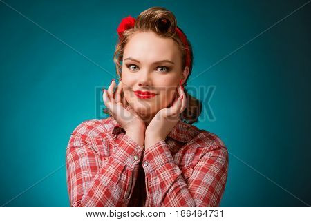 Closeup young pretty pinup girl red button shirt looking at you camera teal color background retro vintage 50's style. Human emotions body language