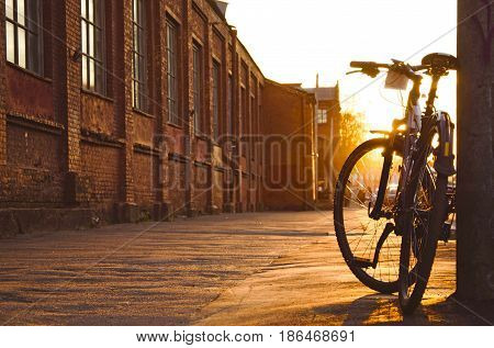 Black fixed gear bicycle in city. Bicycle parked next to sidewalk. Bicycle parked next to industrial factory.