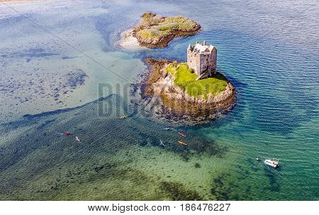 Aerial canoes gathering around the historic castle Stalker in Argyll, Scotland