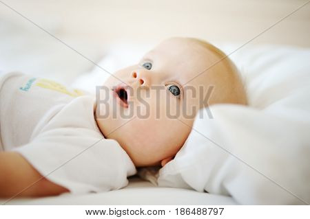 Portrait of a young child in white clothes against the background of a baby crib
