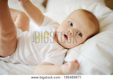 Portrait of a young child in white clothes against the background of a baby crib