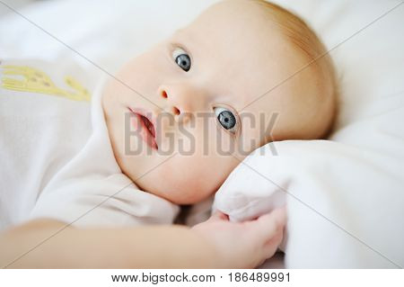 Portrait of a young child in white clothes against the background of a baby crib