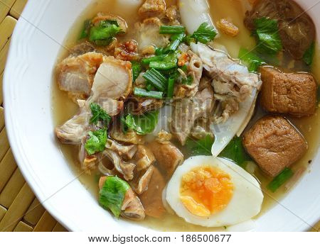 boiled Chinese pasta with pork and entrails topping creamy egg yolk in soup