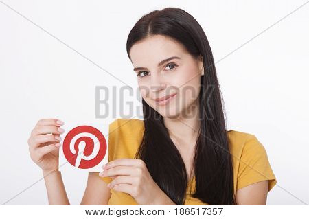 KIEV, UKRAINE - AUGUST 22, 2016: Woman hands holding Pinterest icon printed paper close up. Is photo sharing website.
