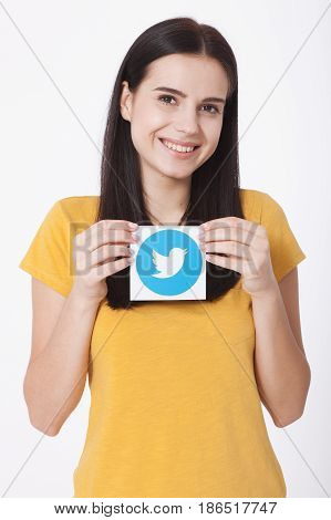 KIEV, UKRAINE - AUGUST 22, 2016: Woman hands holding Twitter logotype icoi bird printed paper close up. Twitter is an online social networking service that enables users to send and read short messages.