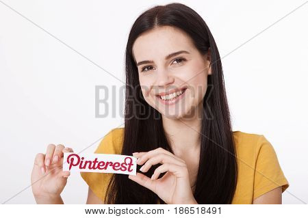 KIEV, UKRAINE - AUGUST 22, 2016: Woman hands holding Pinterest ilogotype icon printed paper close up. Is photo sharing website.