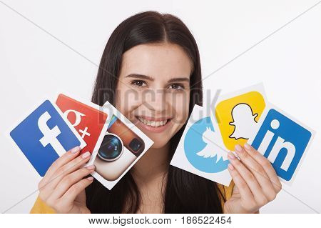 KIEV, UKRAINE - AUGUST 22, 2016:Woman hands holding collection of inscriptions, symbols of popular social media: Twitter, Google, Instagram, Fasebook, Linkedin, Snapchat printed on paper scattered randomly