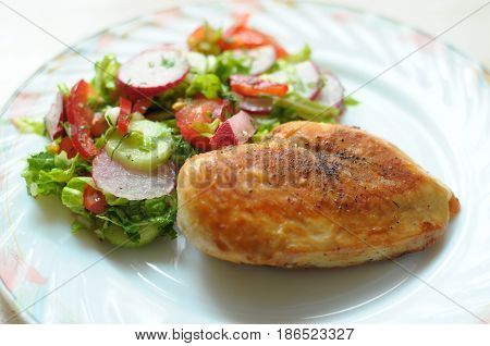 Baked Chicken Breast With Vegetable Salad On A White Plate
