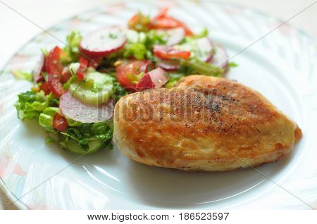 Baked Chicken Breast With Vegetable Salad On A White Plate