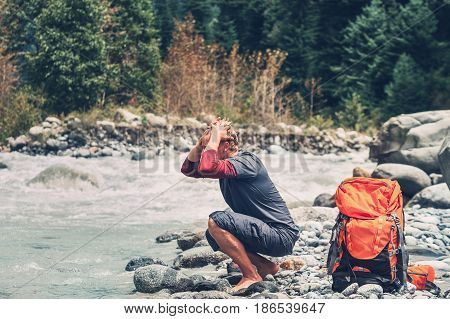 Young man tourist refresh with water in mountain river