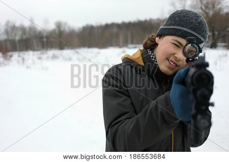 Teenager with gun takes aim during lasertag game outdoor at winter
