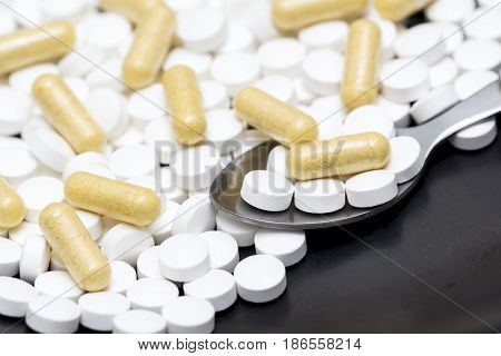Medicine pills on a surface with a doseage in a teaspoon