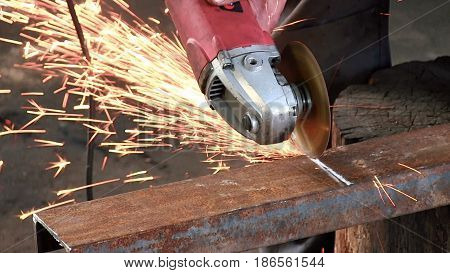 A man cuts a rusty metal beam, using a circular turbine. Angle Grinder red color slowmotion close-up have sound audio