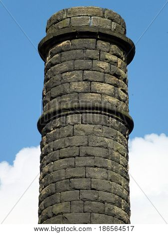 old stone mill chiney in yorkshire with blue sky and clouds