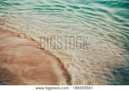 Closeup macro shot of sea ocean green blue wave water sandy beach background with copyspace. Toned with retro vintage film effect style instagram filters