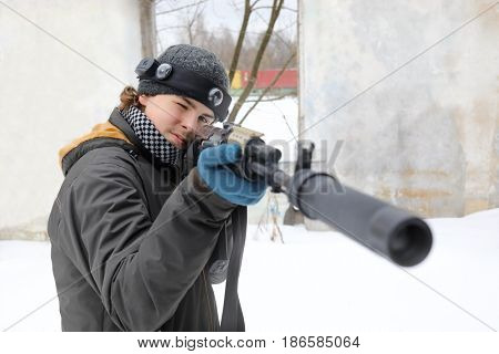 Teenager with gun takes aim during lasertag game outdoor at winter day