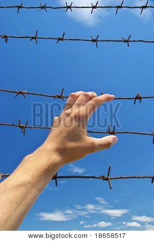 감옥과 하늘 배경의 손입니다. 개념적 장면입니다.