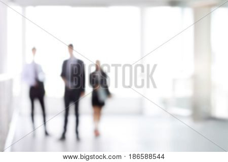Blurred business people standing in white office building hall can be used as background