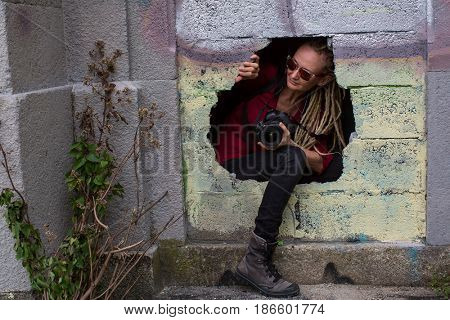 Stalker girl comes from the hole in the wall of Abandoned house with the camera. Adventures and travel.