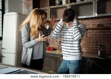 I want to punish you. Nervous young woman raising her hands standing in semi position while going to punish her son
