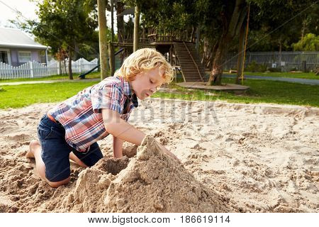 Male Pupil At Montessori School Playing In Sand Pit At Breaktime