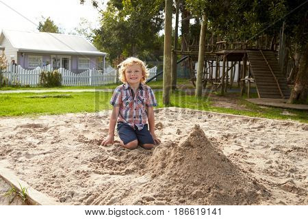 Male Pupil At Montessori School Playing In Sand Pit At Breaktime