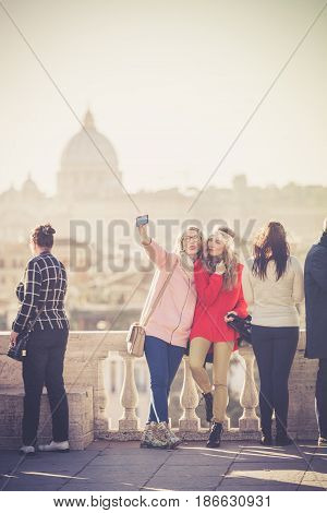 ROME, ITALY. January 10, 2016: Tourists and people on the Pincio terrace in Rome in Italy. View of St. Peter and the city of Rome. Two young girls getting selfie.